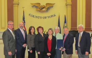(From left)  York County Commissioner Chris Reilly; York Suburban Middle School Principal Scott Krauser; York Suburban Assistant Superintendent Patricia Maloney; former York Suburban Middle School Principal and now Director of Educational Services Victoria Gross; York Suburban Middle School Reading Specialist Karen M. Page (representing the faculty); York Suburban School District Superintendent Shelly Merkle; County Commissioner Doug Hoke; and President Commissioner Steve Chronister.