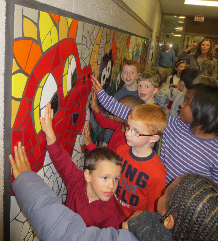 Students point to pieces of the mosaic mural they placed during the work on the project.
